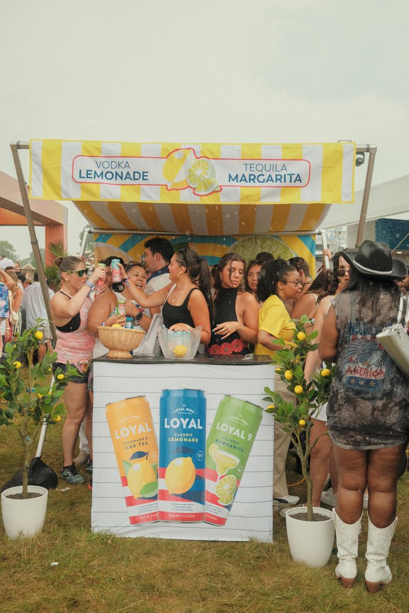 A crowd hides under a small drink stand during the rain